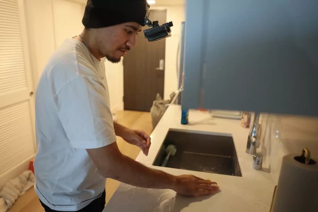 A person wiping a counter with a phone recording rig
